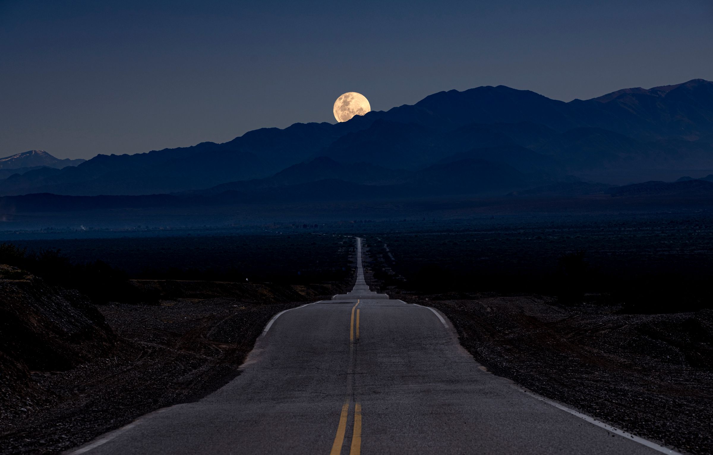 Straße durch eine Berglandschaft bei Vollmond